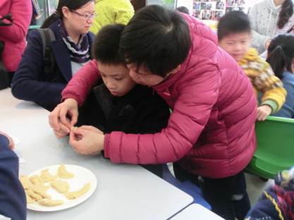 说明: 2017.1.14 越秀区图书馆开展“听·阅读——喜迎元春 同包油角”活动,图为工作人员手把手指导读者包油角。