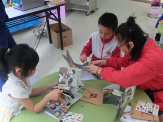 说明: C:\Users\XUYUXIAN\Desktop\5月轮岗文档\学会业界动态上传资料\5.2接收\5.2接收\(信息)创意翩然飞 书香迷人醉\2017.4.22 越秀区图书馆开展“万花筒——认识图书馆”活动,图为工作人员指导小读者制作“认识图书馆”绘本。.JPG